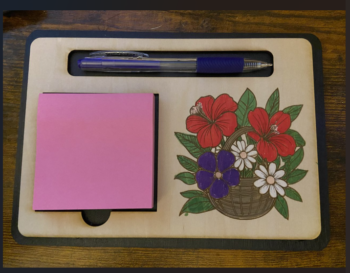 Notebook, pen, and decorative mat with floral design on a wooden surface